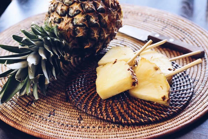 full pineapple and lollipop pineapple in a wood plate on a wooden table