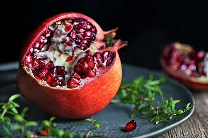 half sliced pomegranate in blue color plate on a wooden table