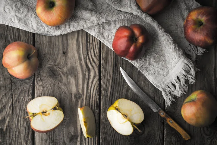 red apples and apple halves on a wooden table