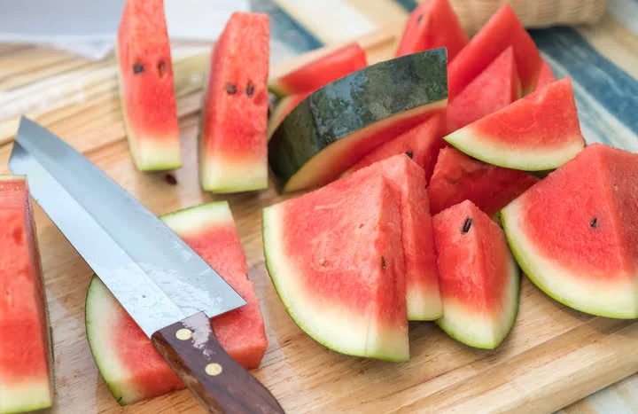 watermelon sliced with knife on a wooden butcher